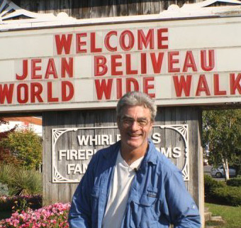 Jean-Beliveau-poses-in-front-of-a-welcome-sign-in-Ontario